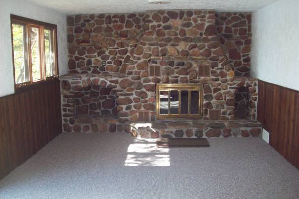 Living area with field stone wood burning fireplace with fans.